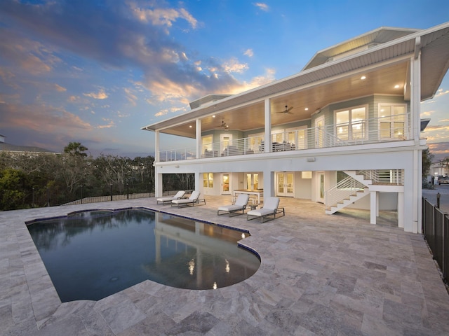 pool at dusk with a patio area and ceiling fan