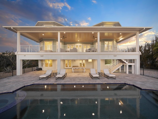 back house at dusk with a patio area, ceiling fan, and a balcony