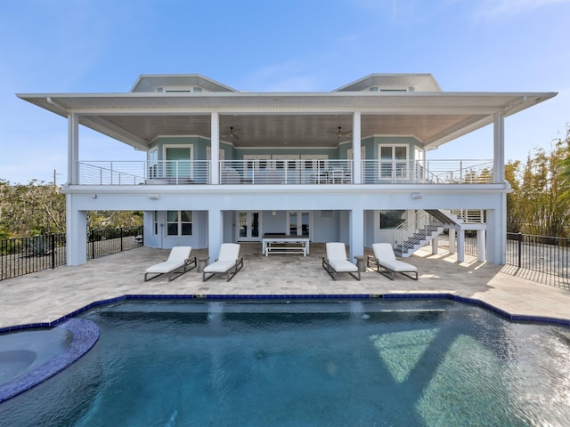 rear view of property featuring ceiling fan, a swimming pool with hot tub, a balcony, and a patio