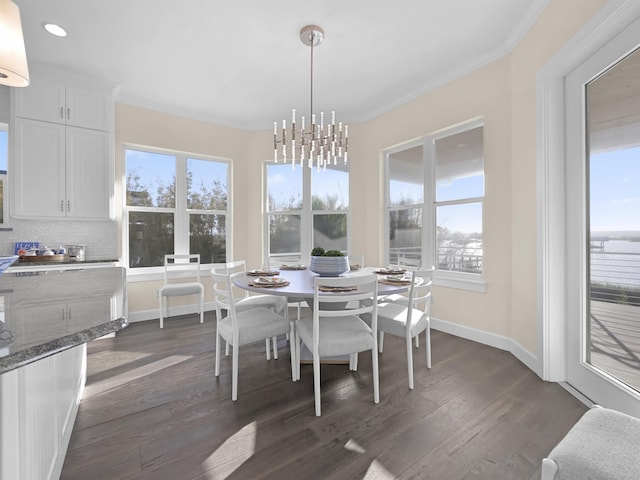 dining room with plenty of natural light, ornamental molding, dark hardwood / wood-style floors, and a notable chandelier