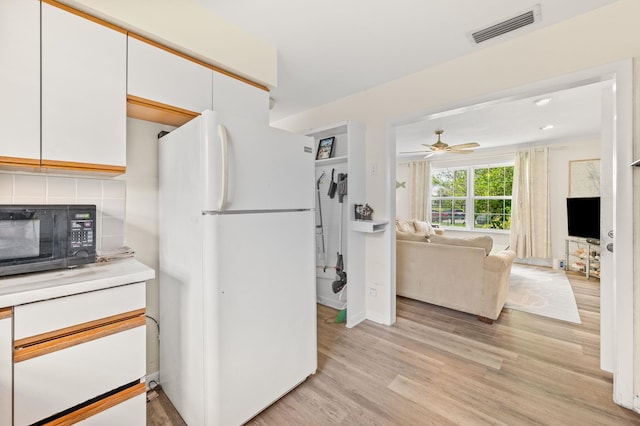 18 Ocean Ave, Saint Augustine, FL 32084 - kitchen with freestanding refrigerator, black microwave, white cabinets, tasteful backsplash, and light wood finished floors
