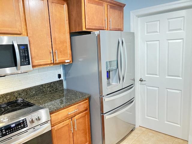 kitchen with tasteful backsplash, light tile patterned floors, dark stone counters, and appliances with stainless steel finishes