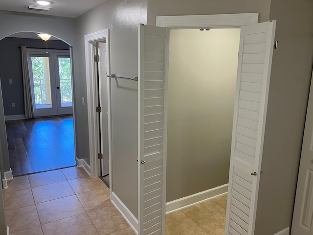 corridor with light tile patterned floors and french doors