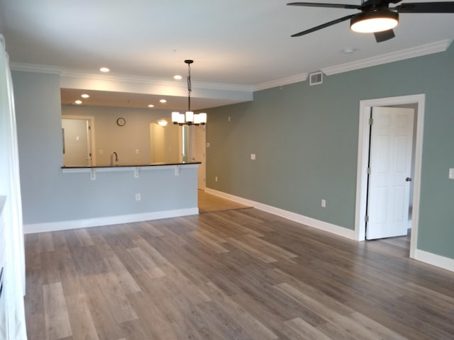 unfurnished living room with sink, wood-type flooring, ceiling fan with notable chandelier, and ornamental molding