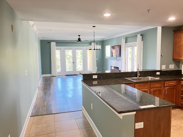 kitchen with dark stone countertops, a wealth of natural light, sink, and hanging light fixtures