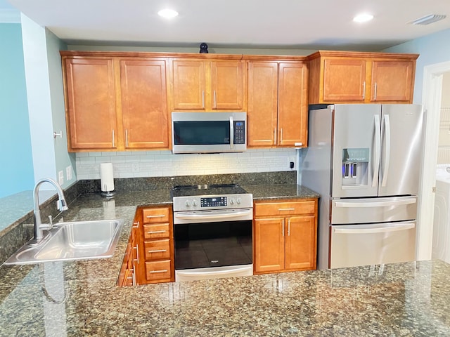 kitchen with decorative backsplash, dark stone countertops, sink, and stainless steel appliances