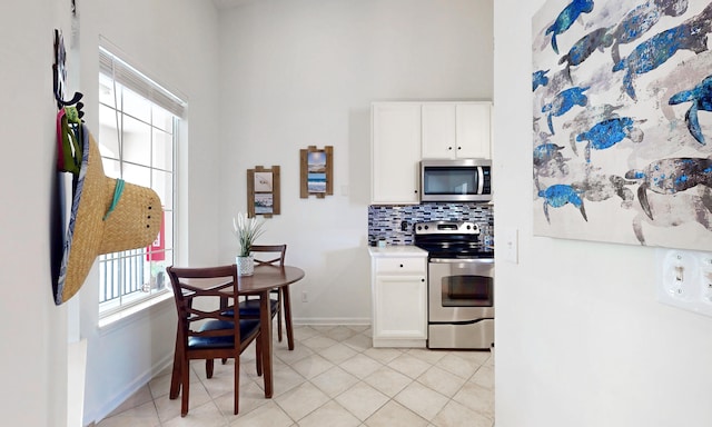 705 Augusta Cir, Saint Augustine, FL 32086 - kitchen with stainless steel appliances, backsplash, a high ceiling, baseboards, and white cabinets