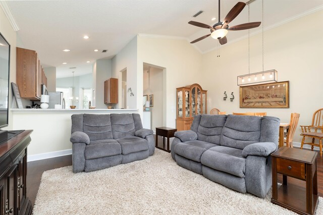 living room with dark hardwood / wood-style floors, vaulted ceiling, ceiling fan, and ornamental molding