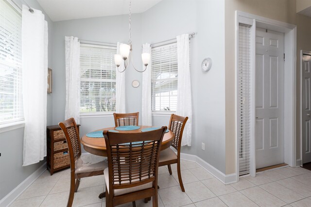 dining area with light tile patterned flooring, vaulted ceiling, a wealth of natural light, and an inviting chandelier