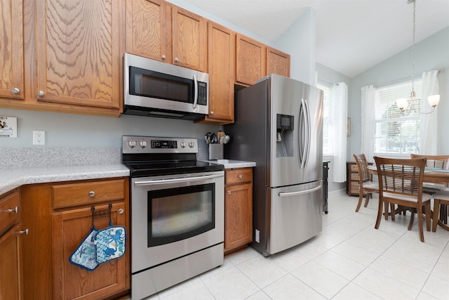 kitchen featuring stainless steel appliances, light tile patterned floors, decorative light fixtures, an inviting chandelier, and lofted ceiling