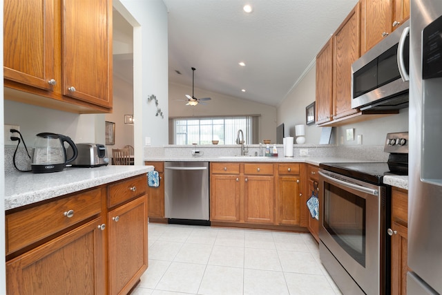 kitchen with lofted ceiling, sink, ceiling fan, appliances with stainless steel finishes, and kitchen peninsula