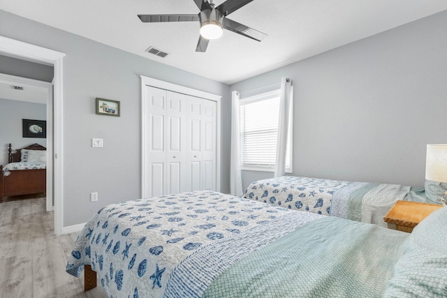 bedroom with ceiling fan, light hardwood / wood-style flooring, and a closet