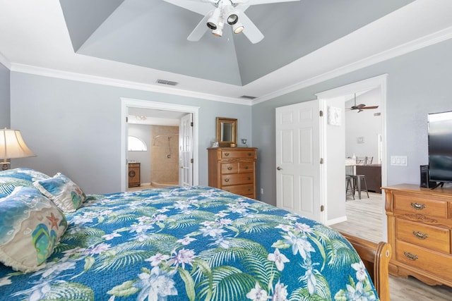 bedroom with ceiling fan, a raised ceiling, light wood-type flooring, and connected bathroom