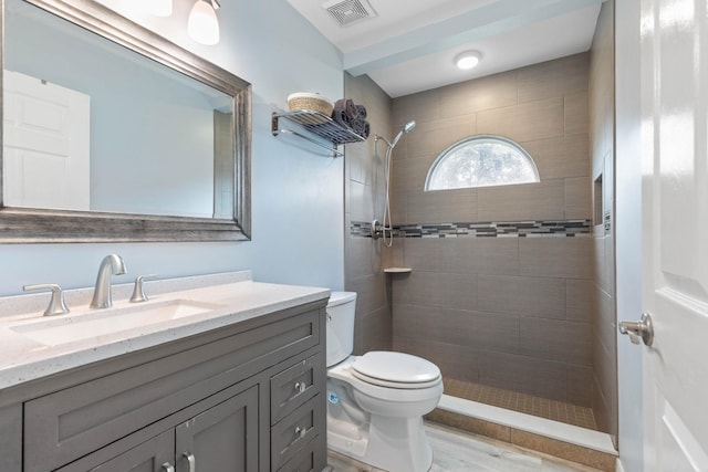 bathroom featuring toilet, vanity, and tiled shower