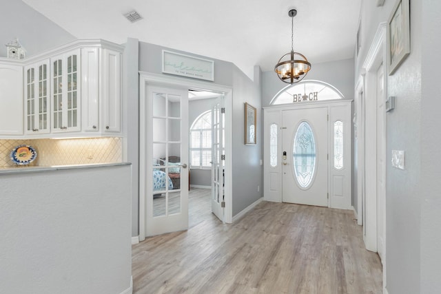 entrance foyer featuring light hardwood / wood-style flooring, lofted ceiling, and an inviting chandelier