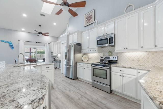 kitchen with white cabinetry, sink, appliances with stainless steel finishes, and a skylight