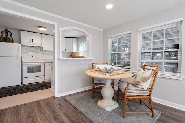 dining space featuring dark wood-type flooring and crown molding