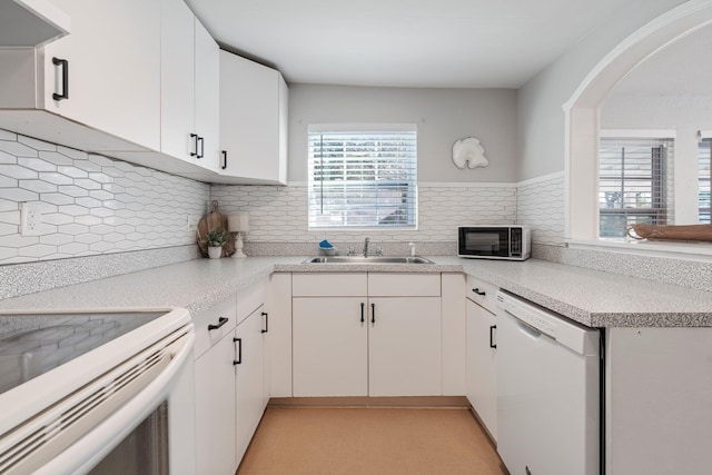 kitchen with sink, white appliances, white cabinetry, backsplash, and range hood