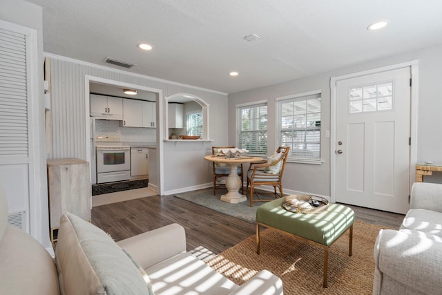 living room featuring dark wood-type flooring and crown molding