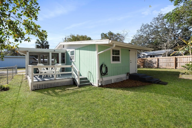 rear view of house with a wooden deck, a yard, and a sunroom