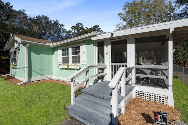 back of property with a lawn and a sunroom