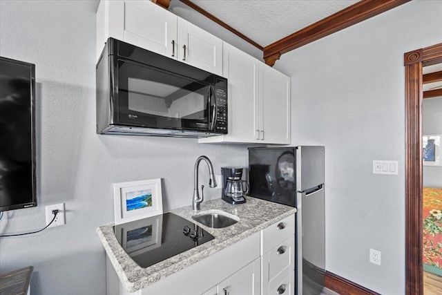 kitchen with sink, crown molding, black appliances, white cabinets, and light stone countertops