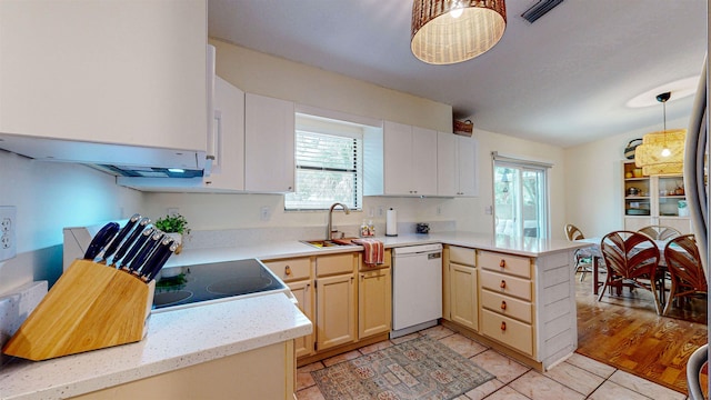 kitchen featuring dishwasher, hanging light fixtures, kitchen peninsula, light tile patterned floors, and range