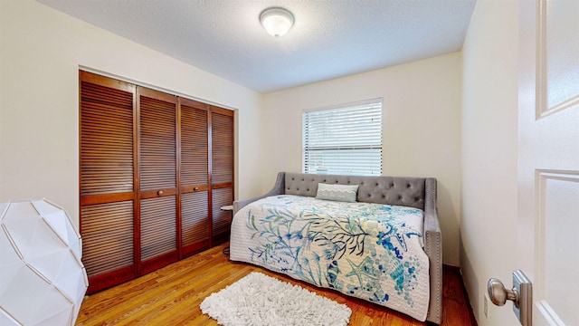 bedroom featuring a textured ceiling, light hardwood / wood-style flooring, and a closet