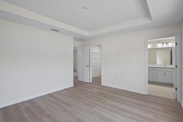 30 Palm Ln, Palm Coast, FL 32164 - unfurnished bedroom with light wood finished floors, a tray ceiling, and a sink