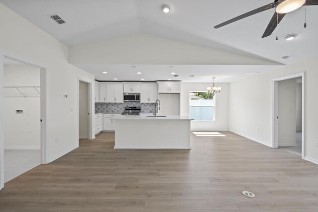 30 Palm Ln, Palm Coast, FL 32164 - kitchen with stainless steel appliances, a sink, vaulted ceiling, white cabinetry, and light wood-style floors