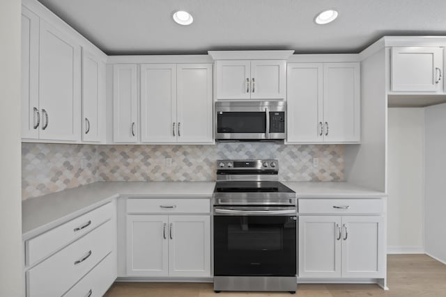 30 Palm Ln, Palm Coast, FL 32164 - kitchen with stainless steel appliances, white cabinets, light countertops, decorative backsplash, and recessed lighting