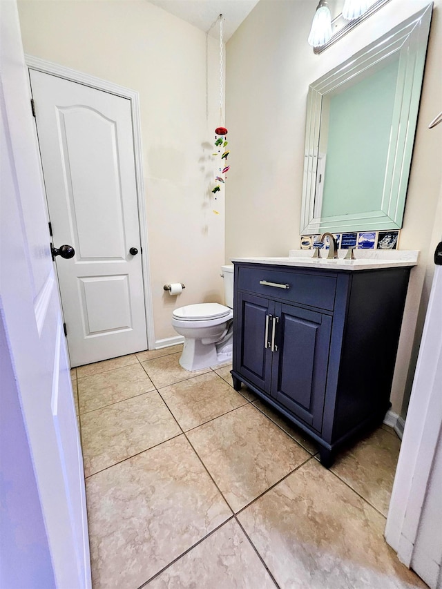 bathroom with vanity, baseboards, tile patterned floors, and toilet
