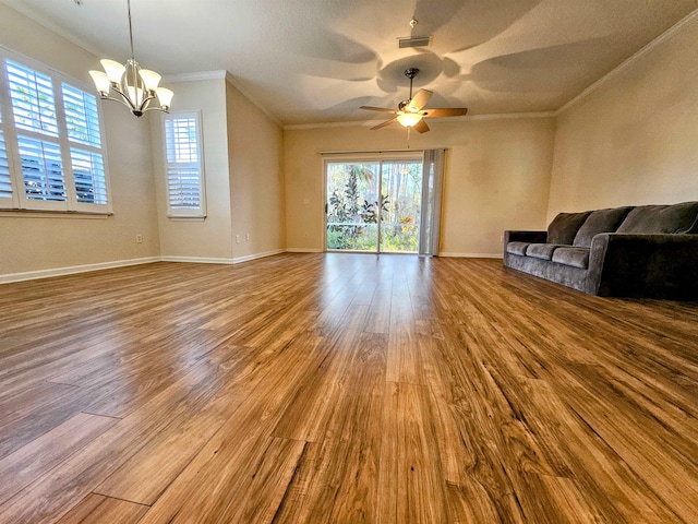 unfurnished living room featuring plenty of natural light, ornamental molding, ceiling fan with notable chandelier, and wood finished floors