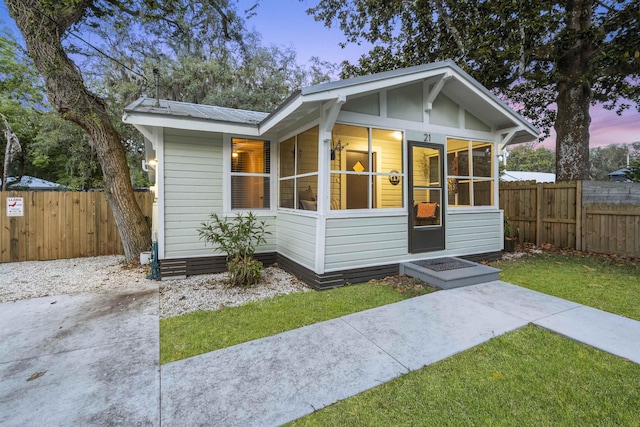 bungalow-style home with a sunroom and a yard