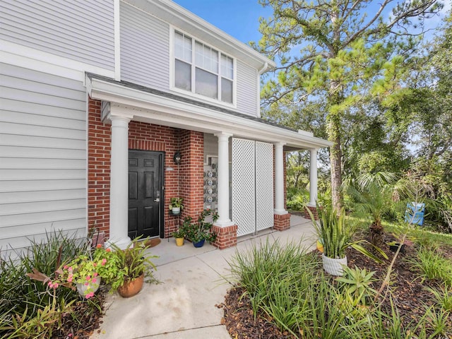 entrance to property featuring brick siding and covered porch
