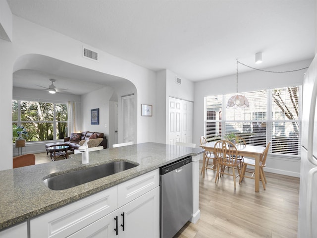 kitchen with stainless steel dishwasher, white cabinetry, dark stone counters, and light hardwood / wood-style flooring