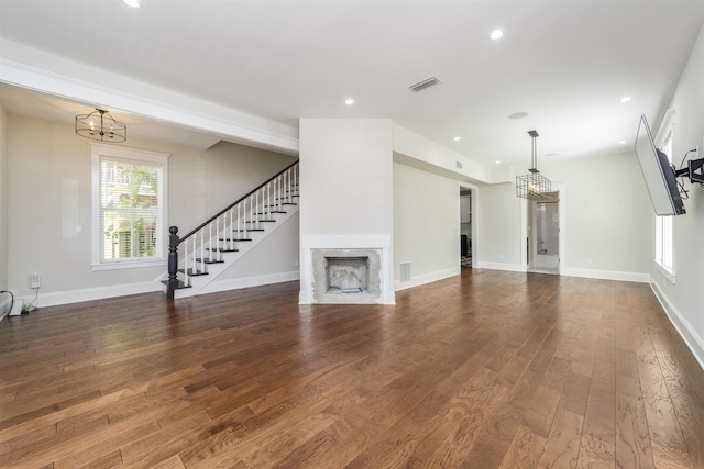 44 Carrera St, Saint Augustine, FL 32084 - unfurnished living room featuring a chandelier, a fireplace, wood finished floors, stairway, and recessed lighting