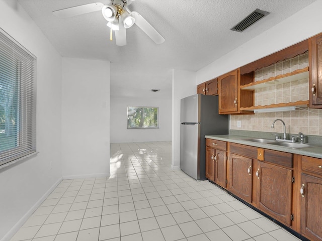 kitchen featuring ceiling fan, sink, tasteful backsplash, stainless steel fridge, and light tile patterned floors