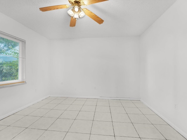 unfurnished room with ceiling fan, light tile patterned flooring, and a textured ceiling