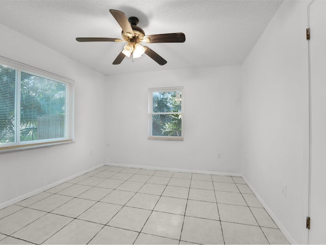 empty room with light tile patterned floors, a textured ceiling, and ceiling fan