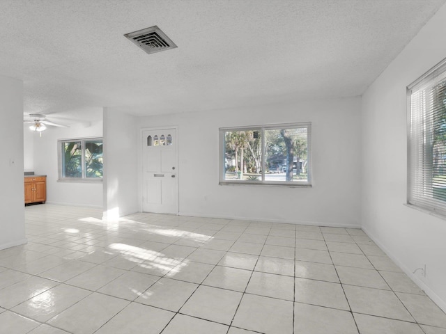 interior space with ceiling fan, a textured ceiling, and a wealth of natural light