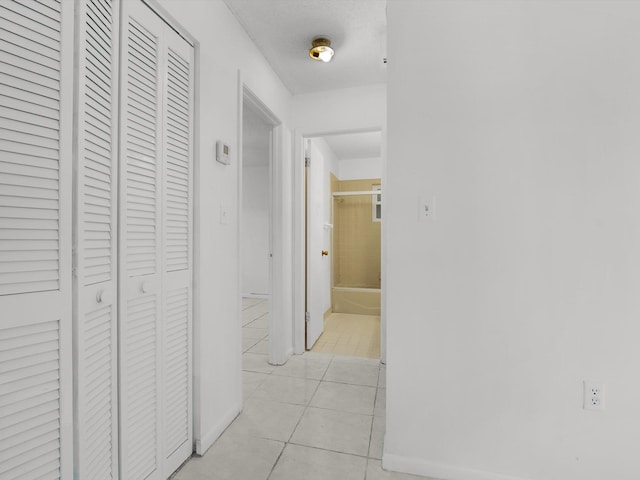 corridor with light tile patterned floors and a textured ceiling