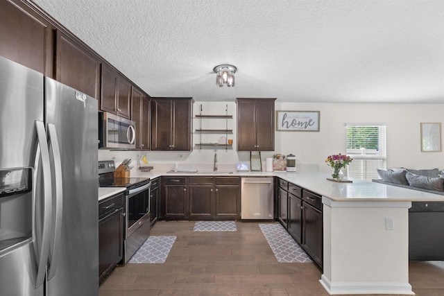 121 Sawmill Forest Ct, Saint Augustine, FL 32086 - kitchen with dark brown cabinetry, appliances with stainless steel finishes, a peninsula, open floor plan, and dark wood-style floors