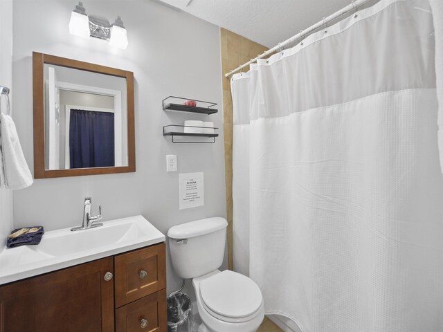 bathroom with vanity, toilet, and a textured ceiling