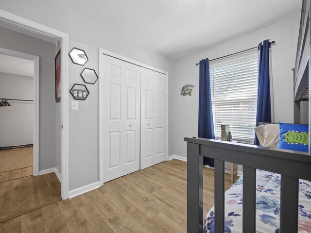 bedroom with a textured ceiling, light hardwood / wood-style flooring, and a closet