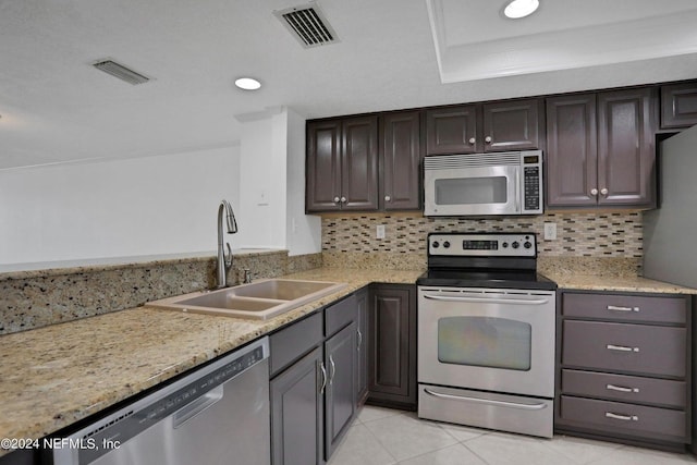 kitchen with sink, backsplash, light tile patterned floors, stainless steel appliances, and dark brown cabinets