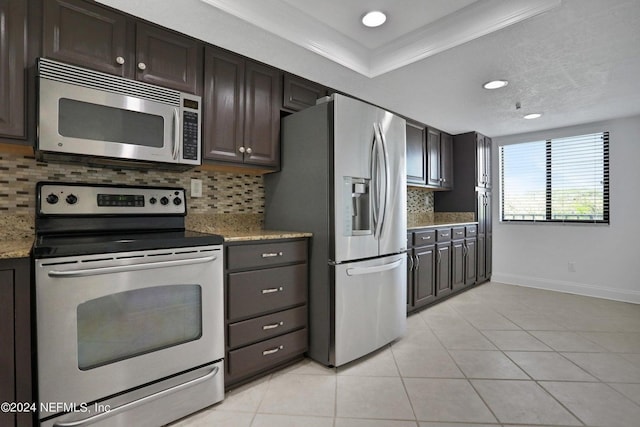 kitchen featuring light tile patterned flooring, appliances with stainless steel finishes, light stone counters, dark brown cabinetry, and crown molding