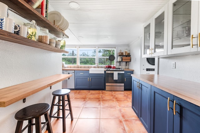 29 Oak St, Saint Augustine, FL 32084 - kitchen featuring open shelves, blue cabinetry, appliances with stainless steel finishes, wood counters, and a textured wall