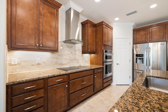 kitchen with wall chimney exhaust hood, dark stone countertops, decorative backsplash, appliances with stainless steel finishes, and ornamental molding