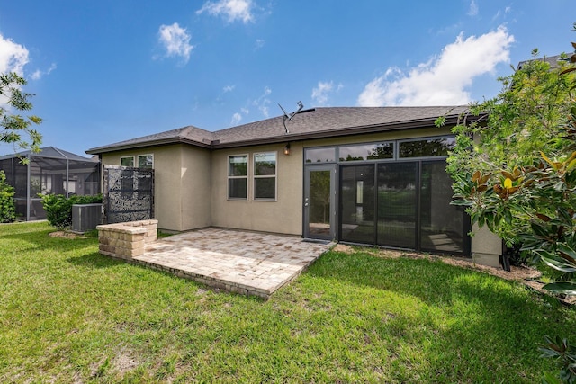 rear view of house featuring a yard, glass enclosure, a patio, and central air condition unit